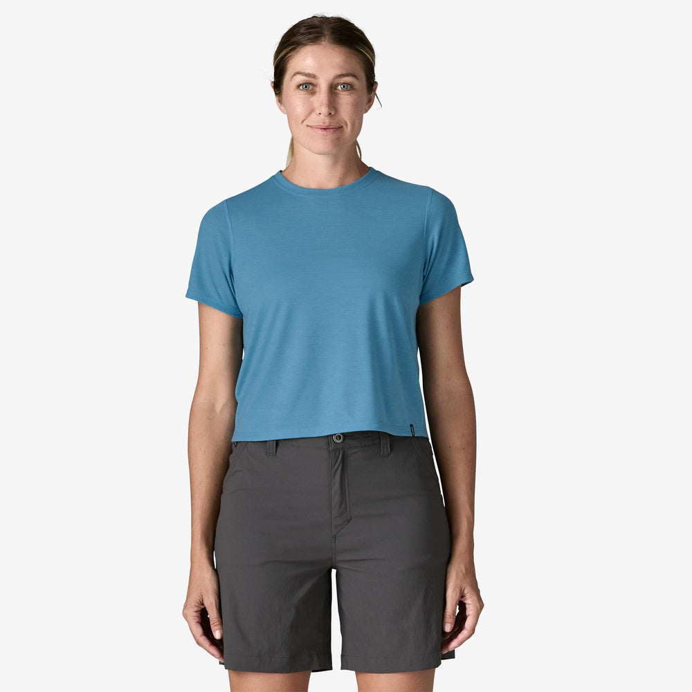 Woman wearing a blue t-shirt and grey shorts on a white background