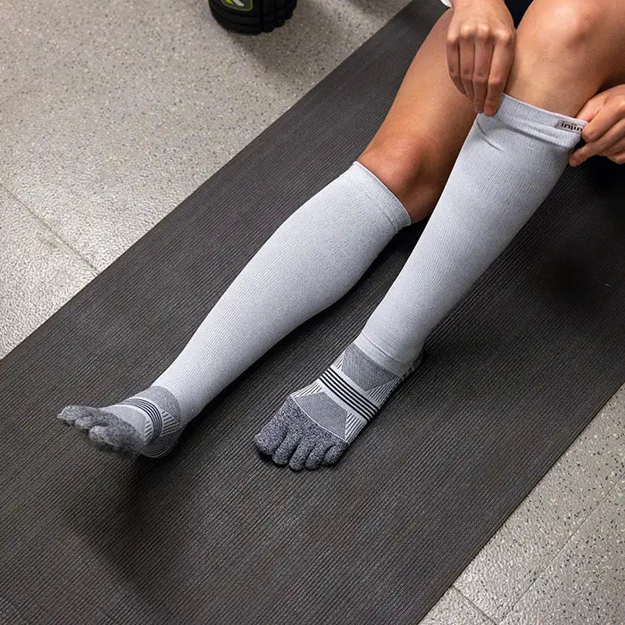 Person wearing gray knee-high socks on a yoga mat