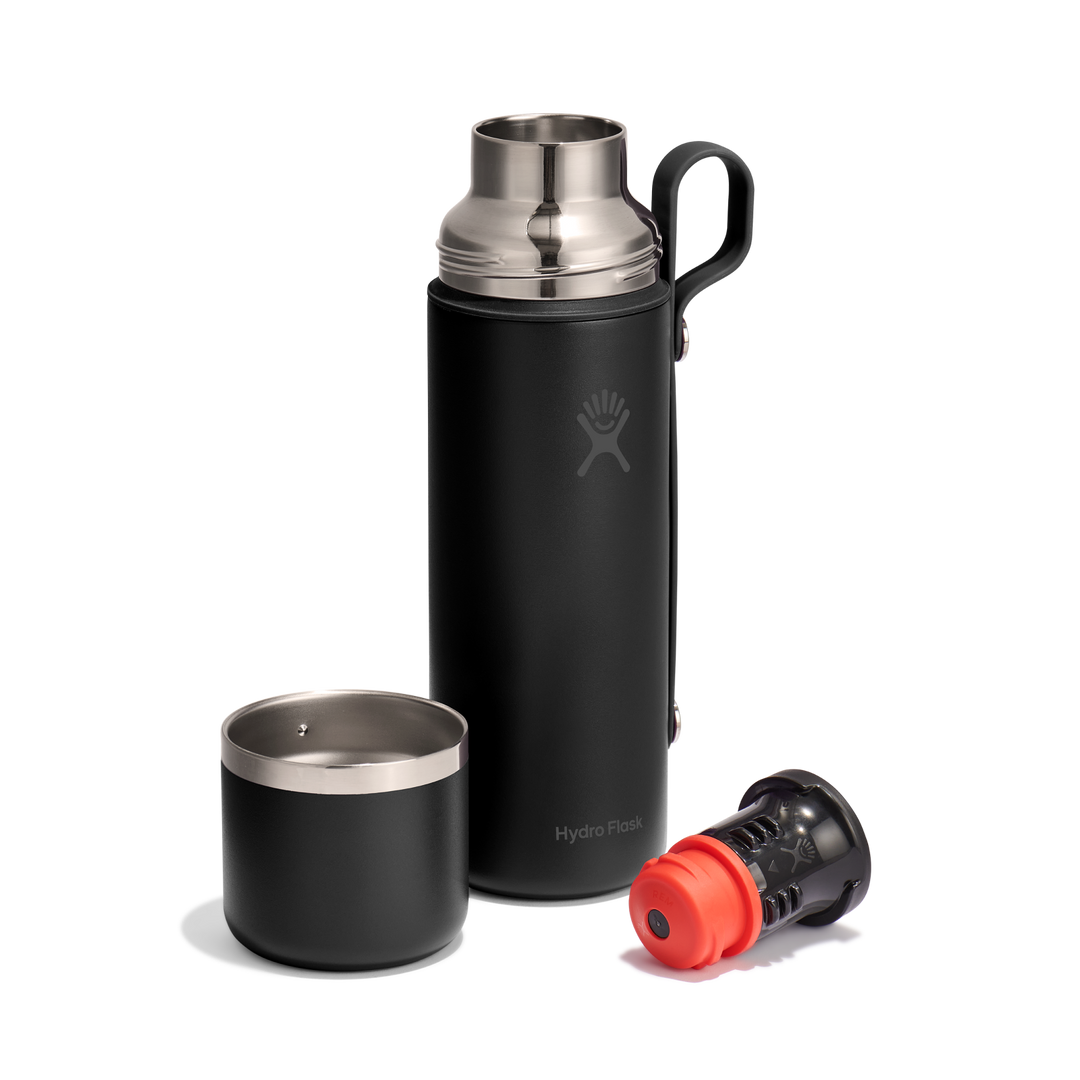 Black thermos bottle with lid and valve style cap removed and lying next to it
