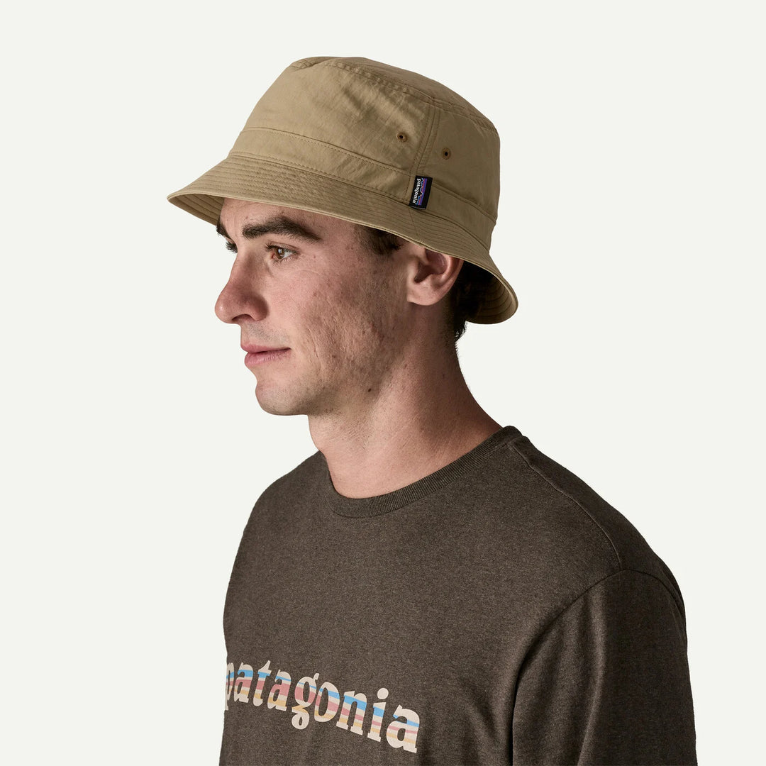 Man wearing a beige bucket hat and Patagonia shirt on a white background