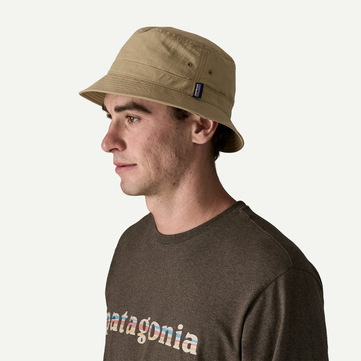 Man wearing a beige bucket hat and Patagonia shirt on a white background