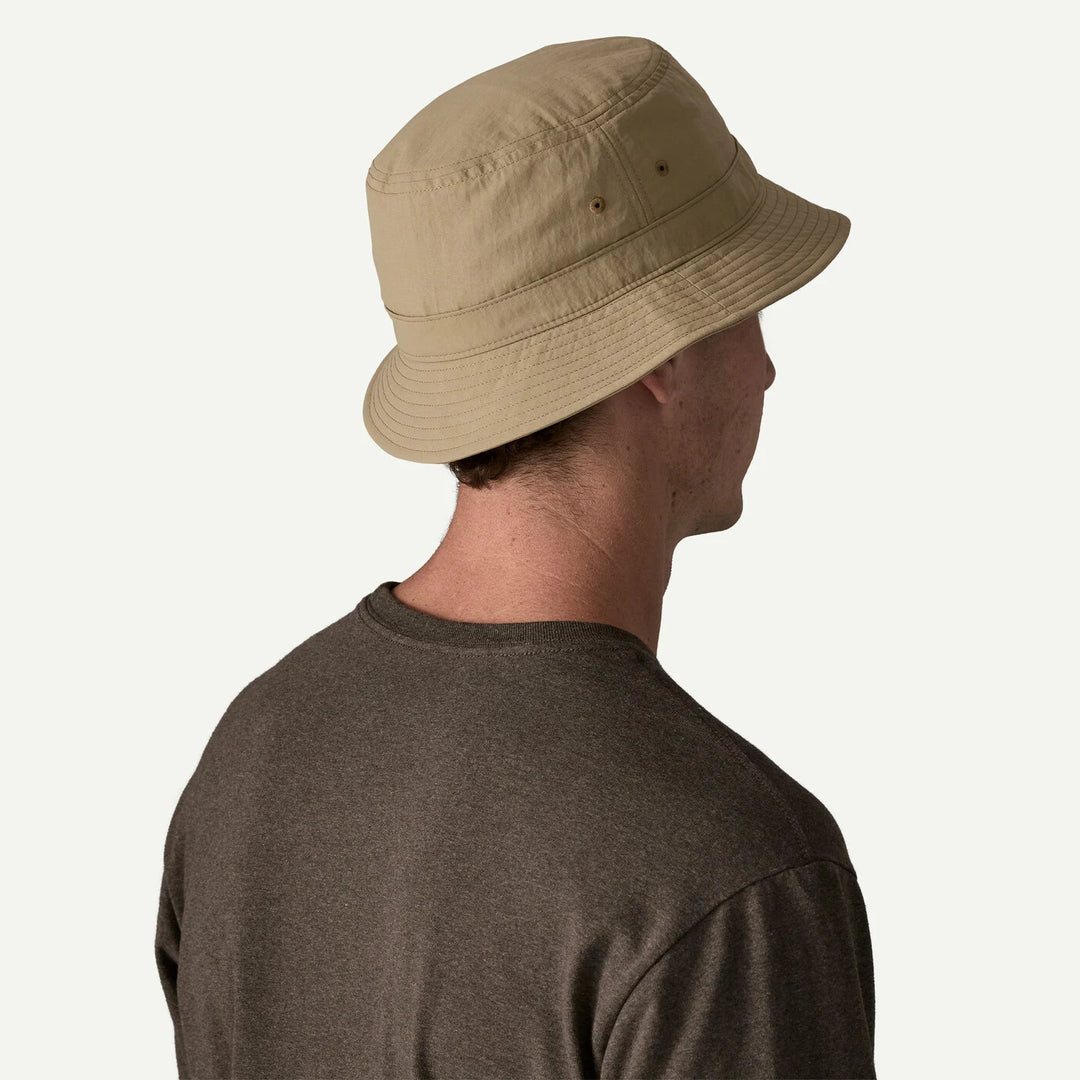 Person wearing a beige bucket hat on a white background