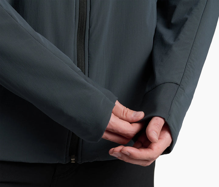 Close-up of a person wearing a dark gray jacket with hands clasped together.