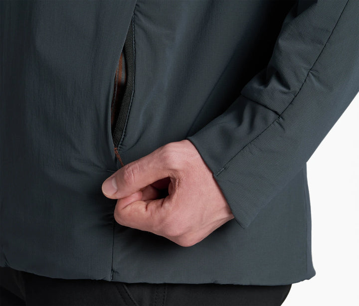 Close-up of a person wearing a dark green jacket with a hand unzipping the pocket
