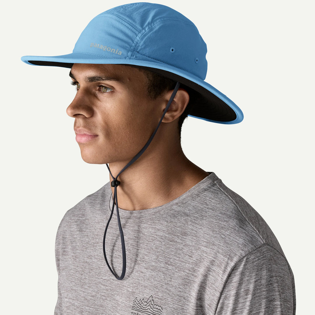 Person wearing a blue wide-brimmed hat with a gray shirt on a white background