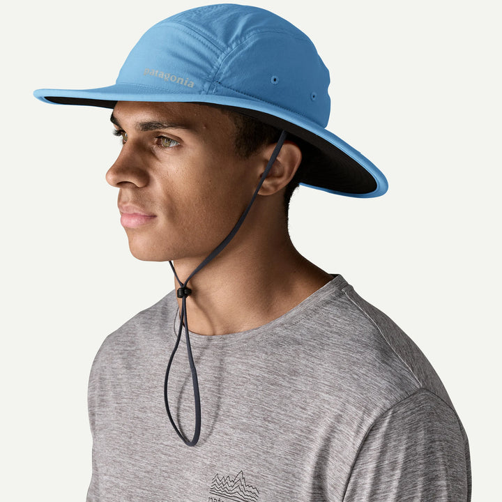 Person wearing a blue wide-brimmed hat with a gray shirt on a white background