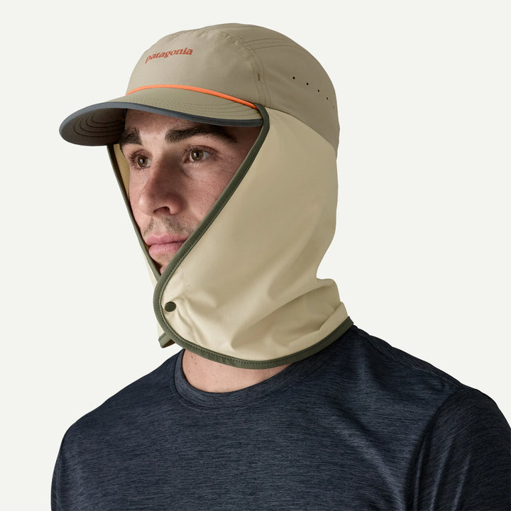 Person wearing a beige Patagonia cap and hood on a white background