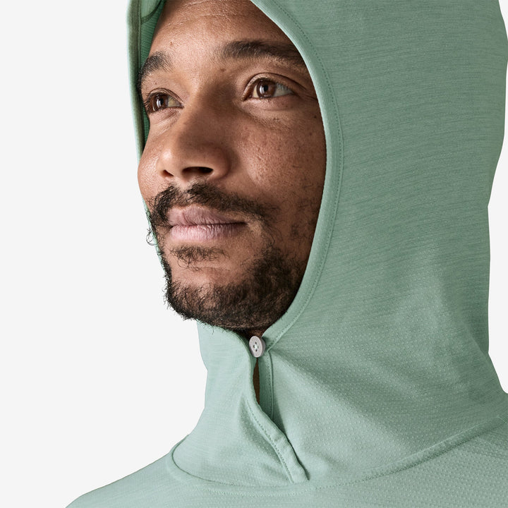 Man wearing a light green hooded garment on a white background