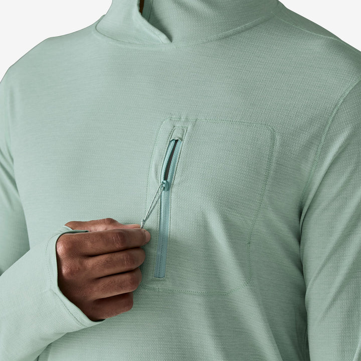 Light green pullover with a zipper pocket and a hand opening it.