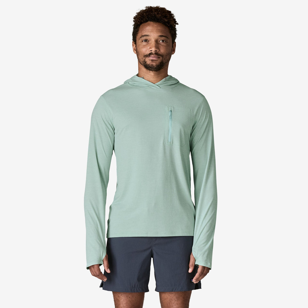 Man wearing a light green long-sleeve hoodie and navy shorts on a white background
