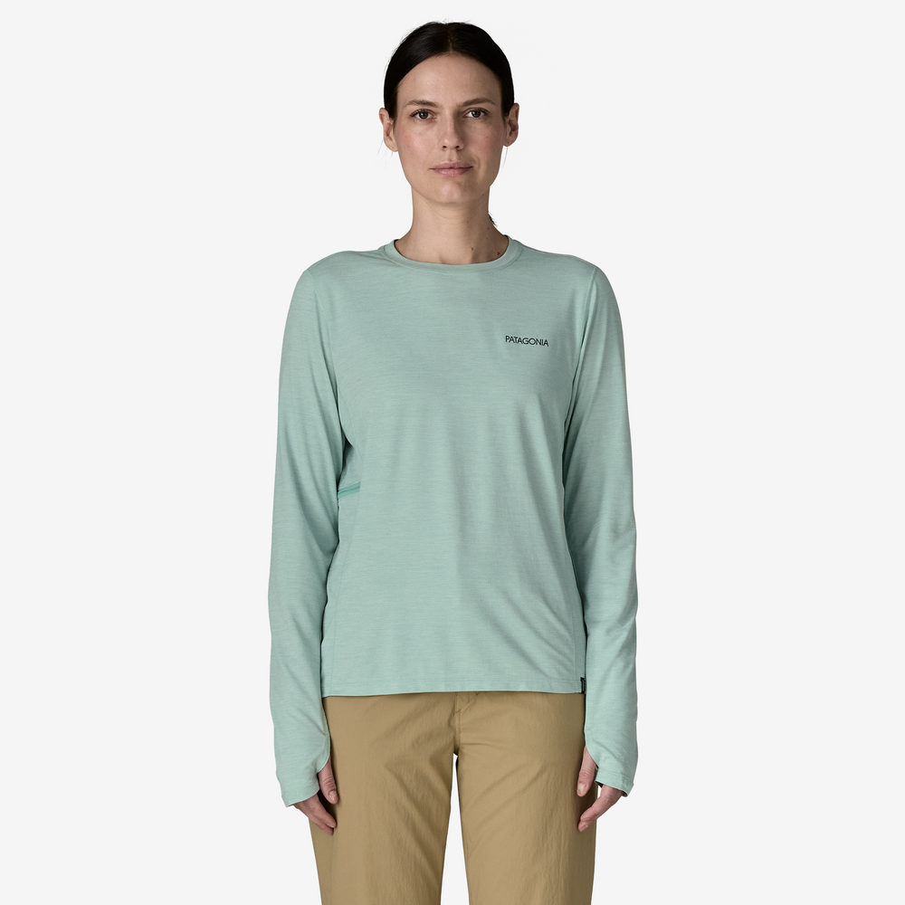 Woman wearing a light green long-sleeve shirt with a brand logo on a white background