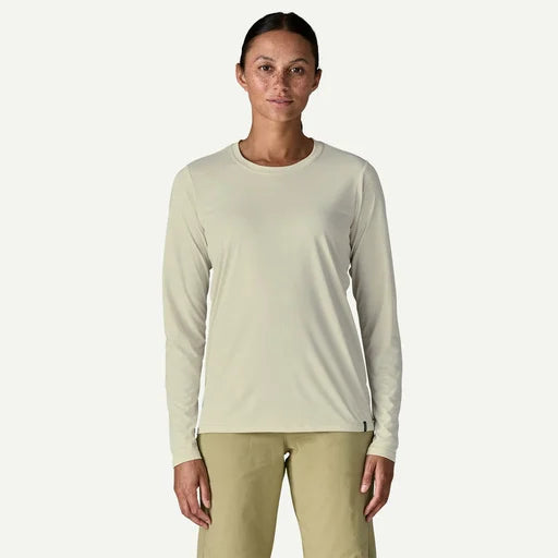 Woman wearing a cream coloured long-sleeve shirt and beige pants on a white background