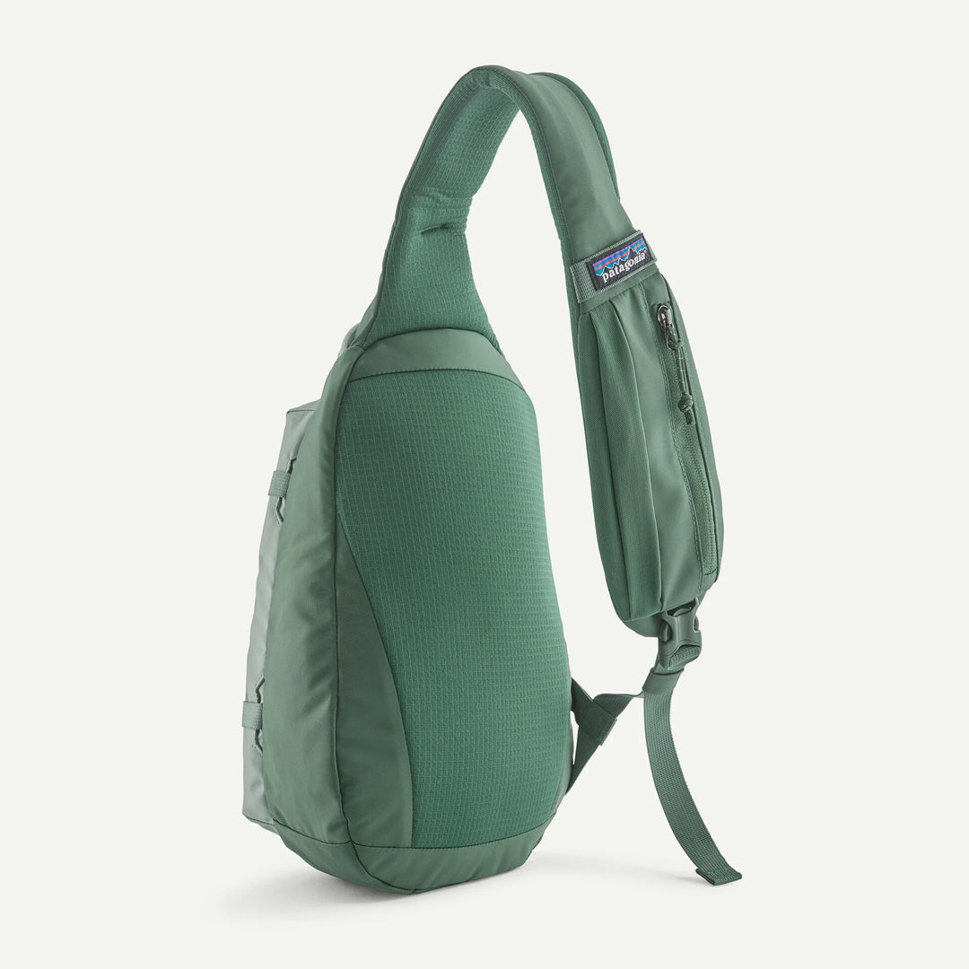 A green Patagonia single-strap sling backpack shown from a side profile view against a light off-white background.