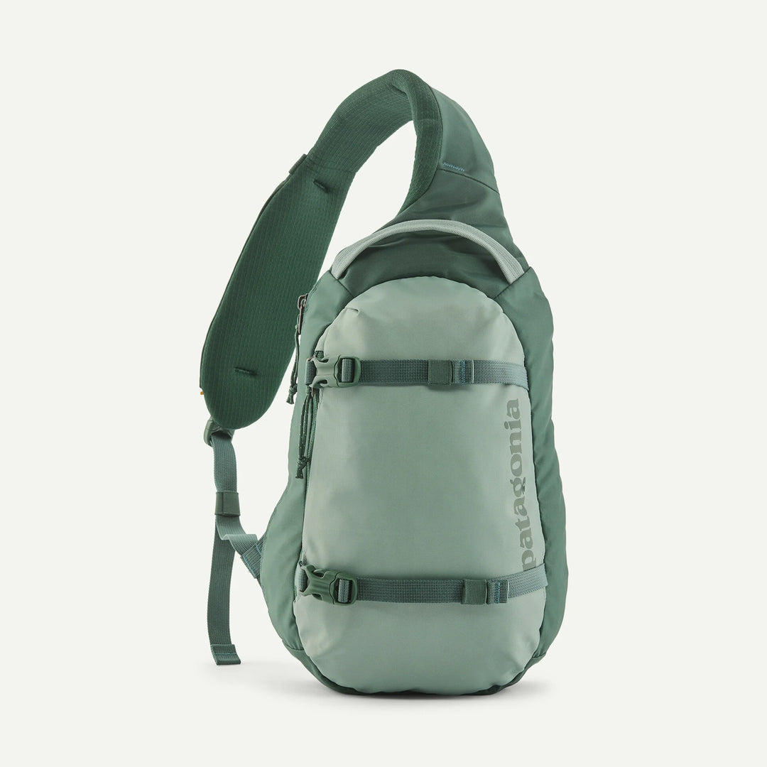 A Patagonia single-strap sling backpack in a muted sage green color, shown from the side against a clean off-white background.