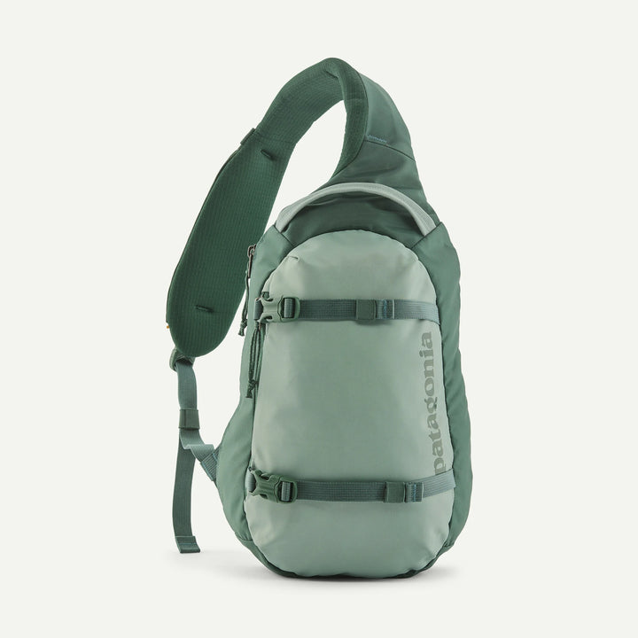 A Patagonia single-strap sling backpack in a muted sage green color, shown from the side against a clean off-white background.