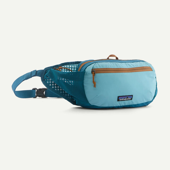 A light blue and teal Patagonia hip pack with brown zipper pulls, shown on a clean off-white background.