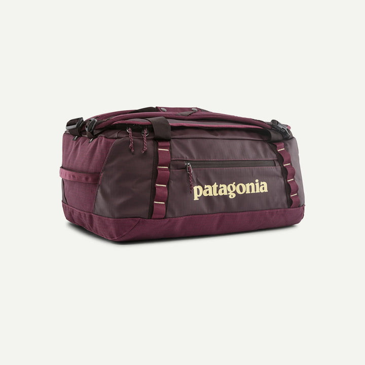A Patagonia duffel bag in a deep burgundy color, featuring a front zippered pocket with the brand name printed in gold, set against a plain off-white background.