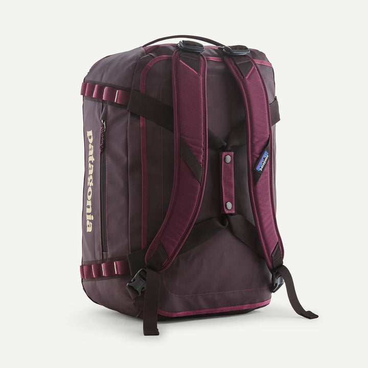 A Patagonia backpack shown from the back, featuring dark purple and black nylon with magenta accents, a vertical Patagonia logo on the side, and padded shoulder straps.
