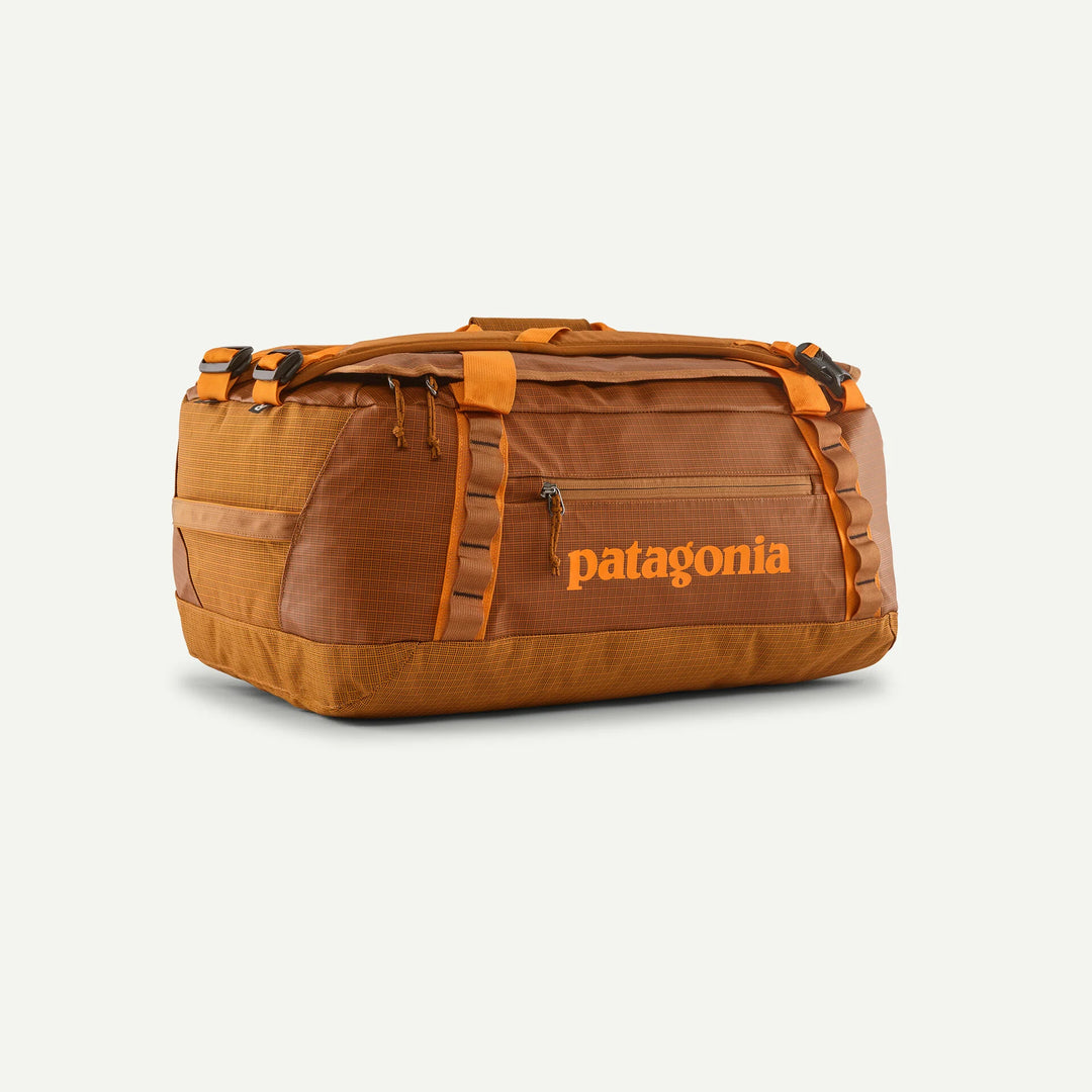 A Patagonia duffel bag in a warm brown and orange colorway, featuring the brand name in orange on the front, set against a light off-white background.