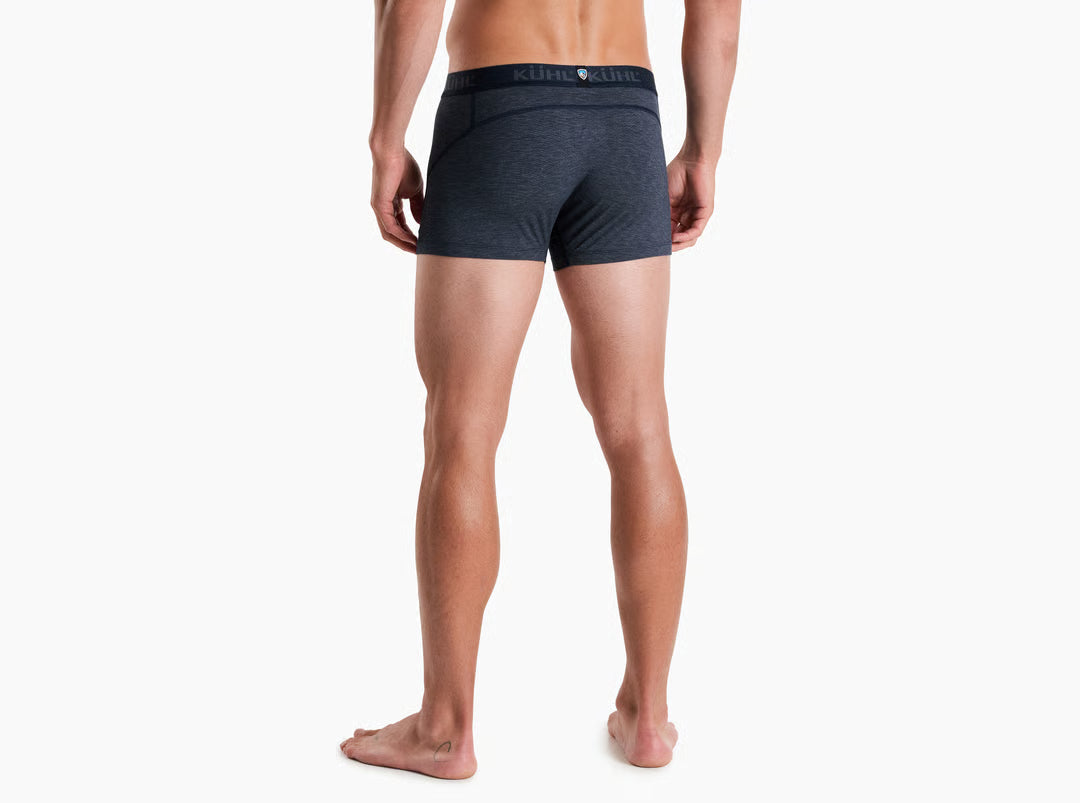 A man modeling dark gray heathered boxer briefs with a black waistband featuring the KUHL logo, shown against a plain white background.