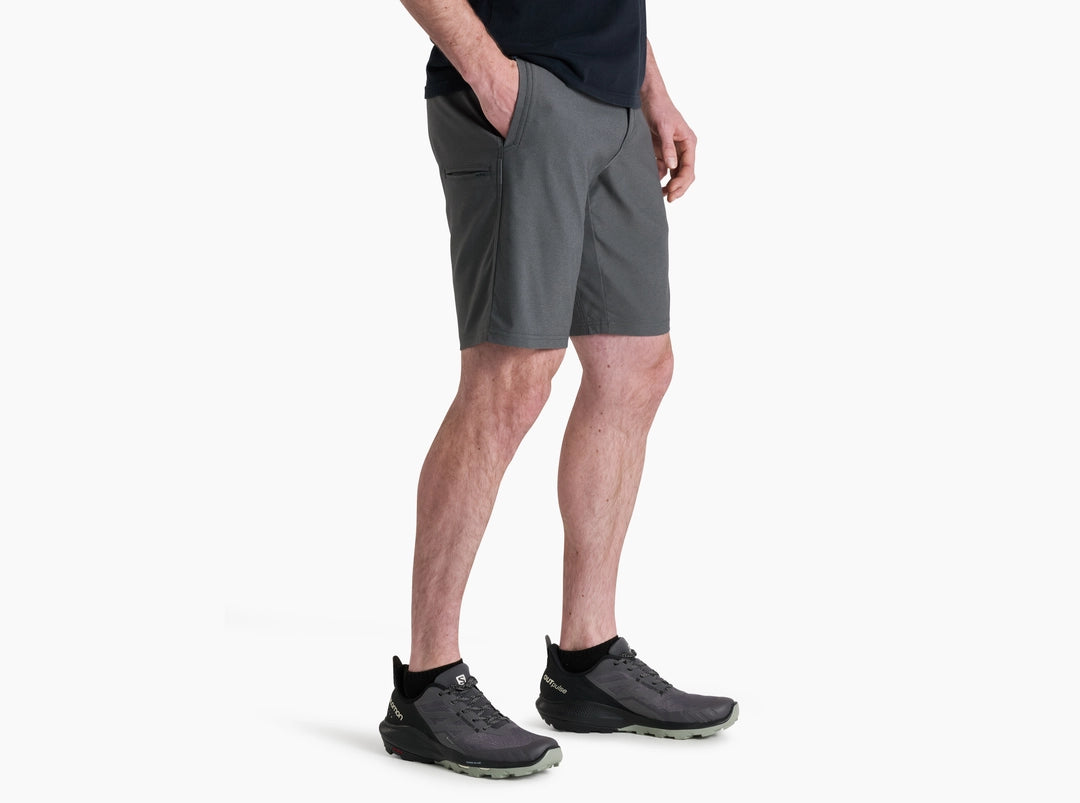 Person wearing gray shorts and black shoes on a white background