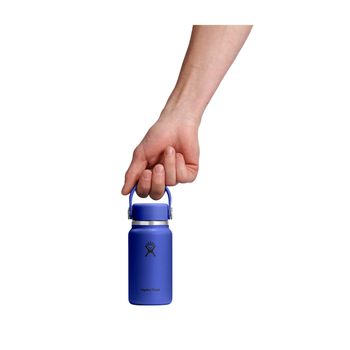 A hand holding a small blue insulated water bottle with a matching blue handle against a solid white background.