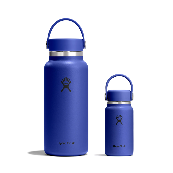 Two Hydro Flask insulated water bottles in a matte royal blue color, one large and one small, both with matching blue carry loops and silver neck rings, shown on a clean white background.
