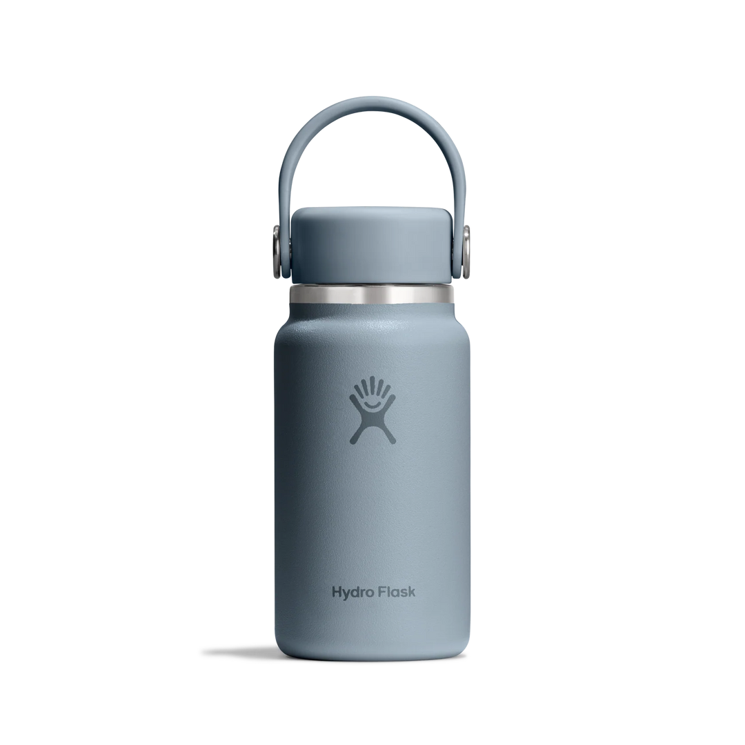 A matte slate blue Hydro Flask water bottle with a matching carrying loop lid, shown on a clean white background.