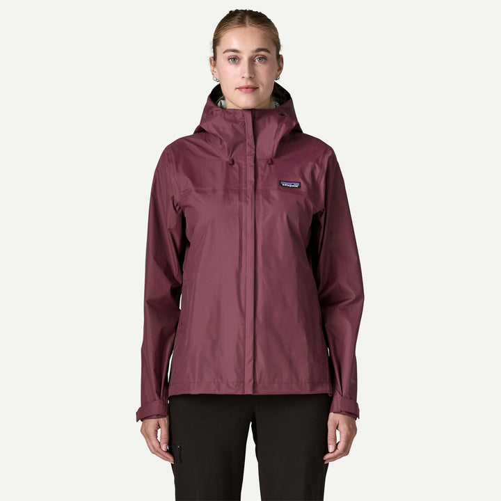 A woman modeling a Patagonia hooded jacket in a dusty burgundy color, paired with black pants, against a solid off-white background.
