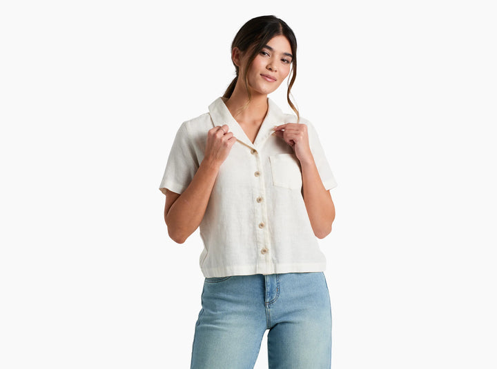 Woman wearing a white button-up shirt and light blue jeans on a white background