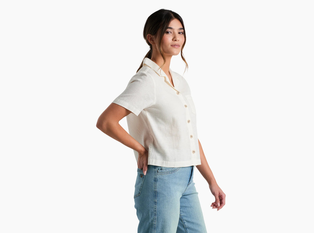 Woman wearing a white button-up shirt and blue jeans on a white background