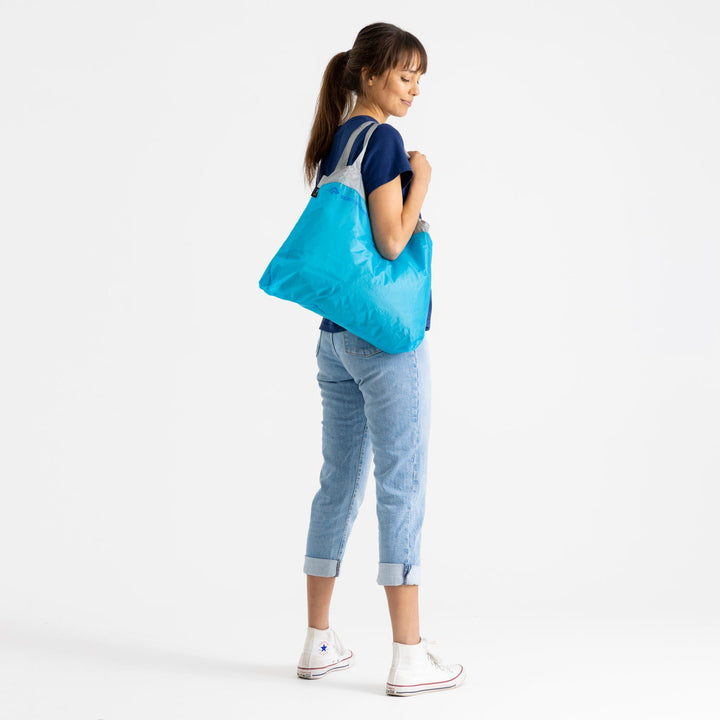 Woman carrying a blue reusable bag on a white background