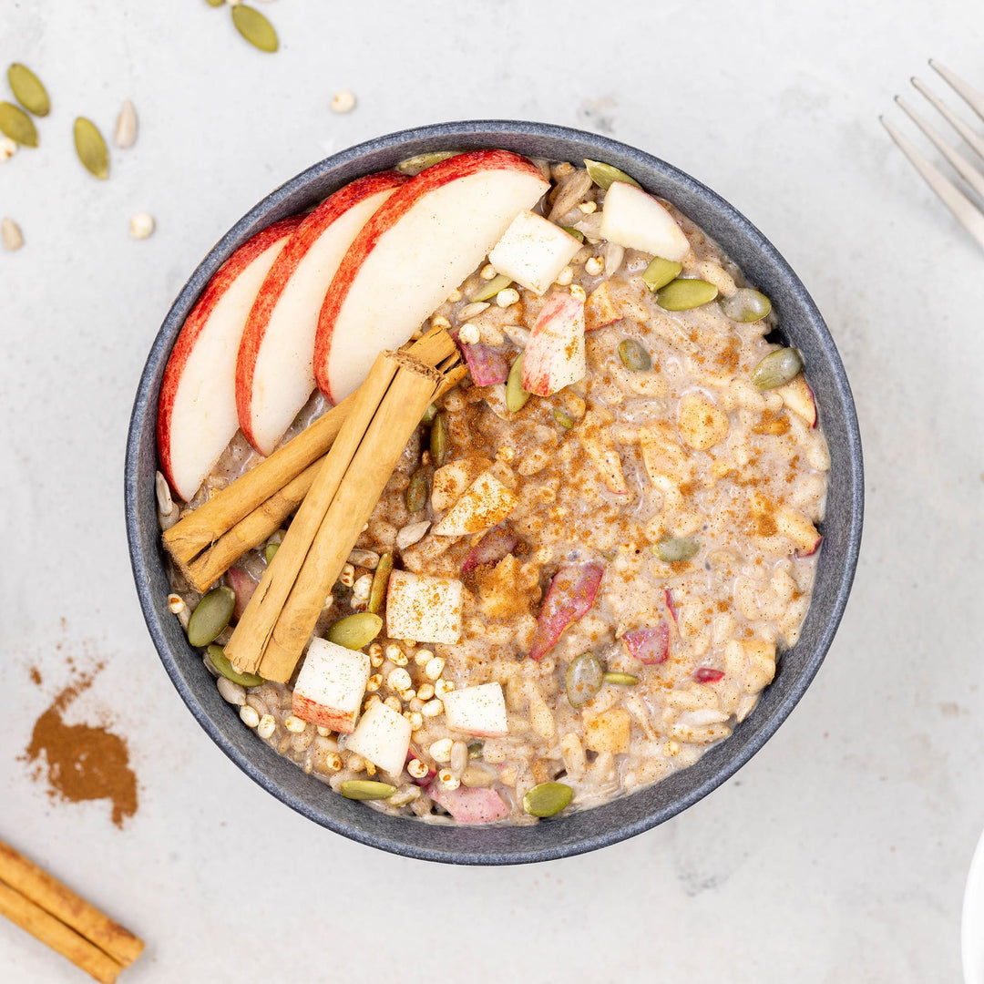Bowl of oatmeal with apples, cinnamon, and seeds on a light background