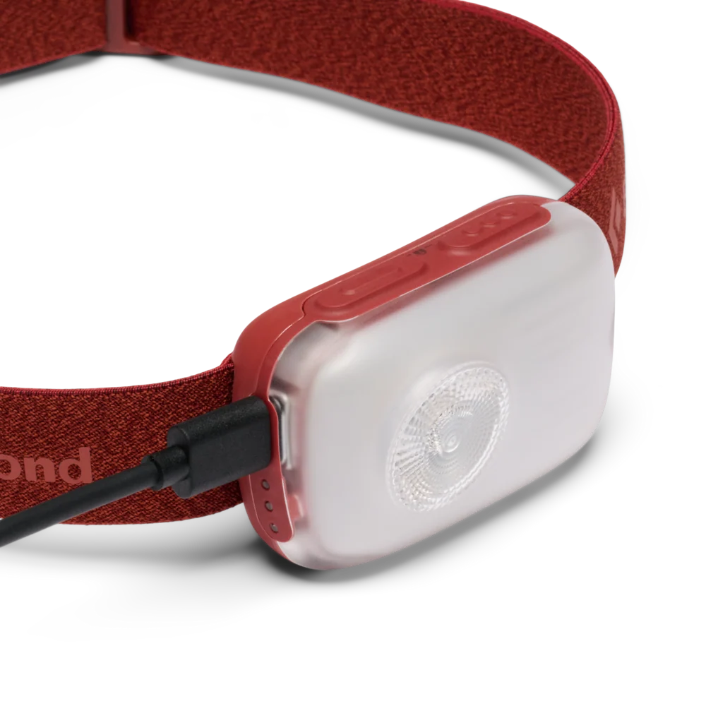 A close-up of a red headlamp with a translucent white light module and a black cable connector, shown on a clean white background.