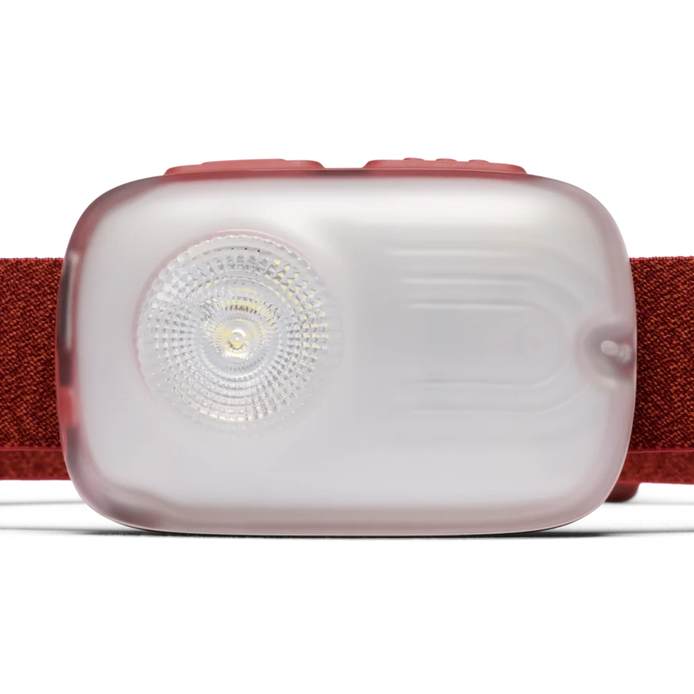 A close-up of a headlamp with a translucent frosted light housing, a visible LED lens, and a textured red elastic strap on a clean white background.