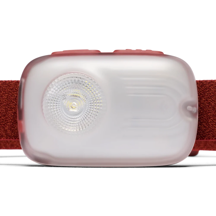 A close-up of a headlamp with a translucent frosted light housing, a visible LED lens, and a textured red elastic strap on a clean white background.