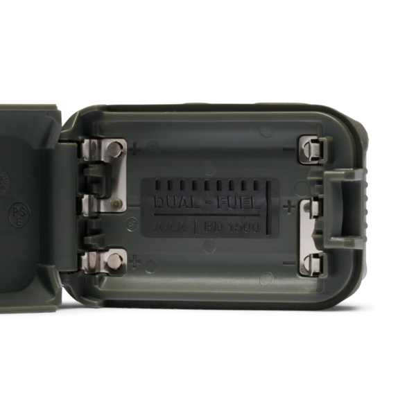 Close-up of the open back of a dark gray waterproof electronic device showing the battery compartment with metal contacts and the text &