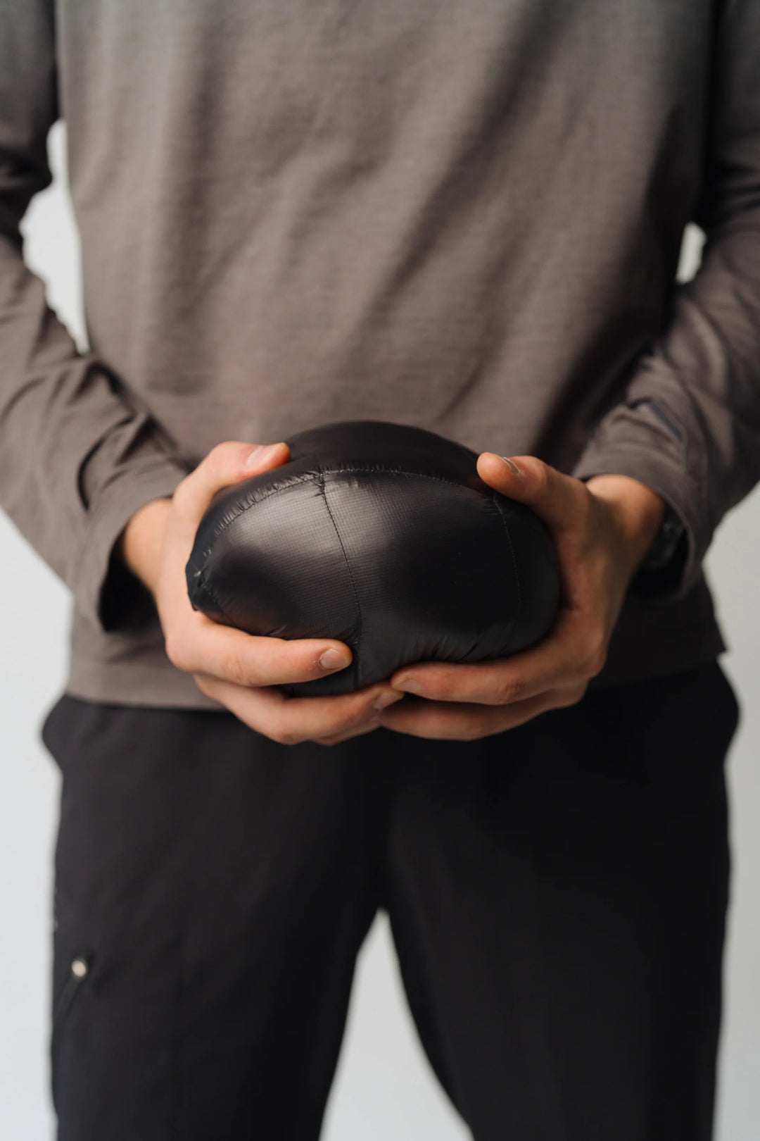 Person holding a black ball against a neutral background