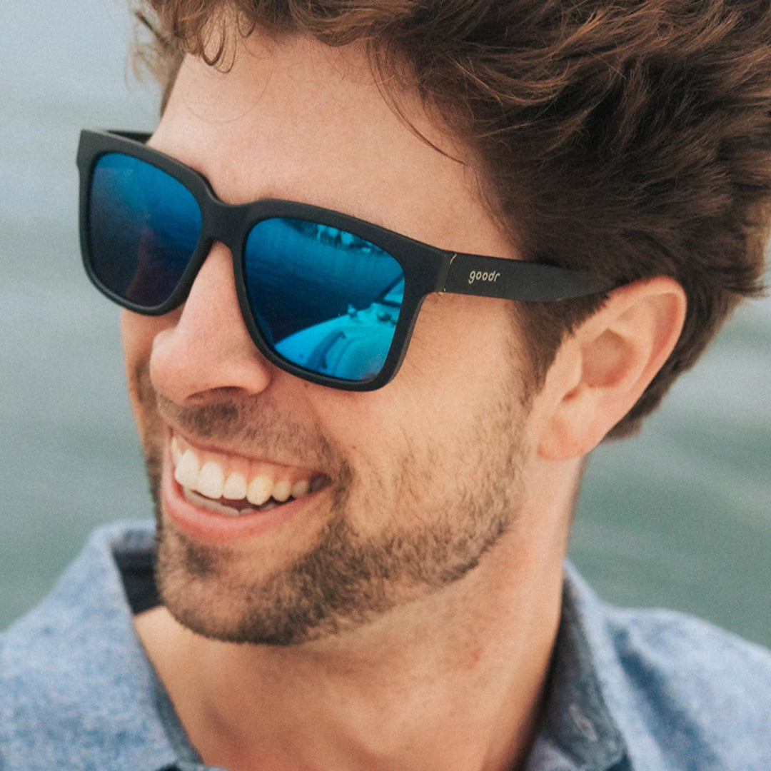 Man wearing black blue-tinted sunglasses with a blurred background