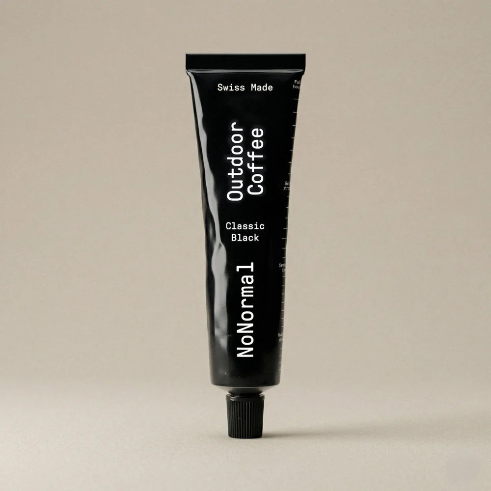 Black Tube with NoNormal Outdoor Coffee written on it on a beige background. 