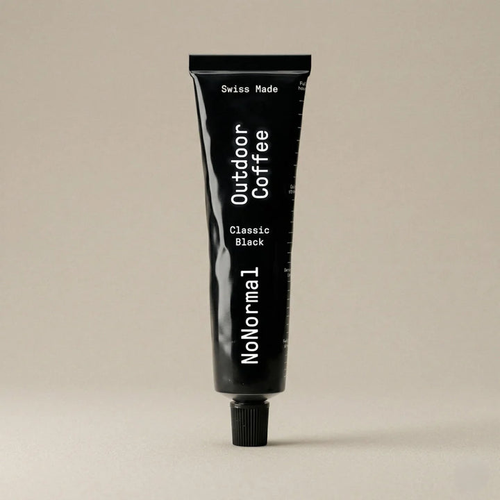 Black Tube with NoNormal Outdoor Coffee written on it on a beige background. 