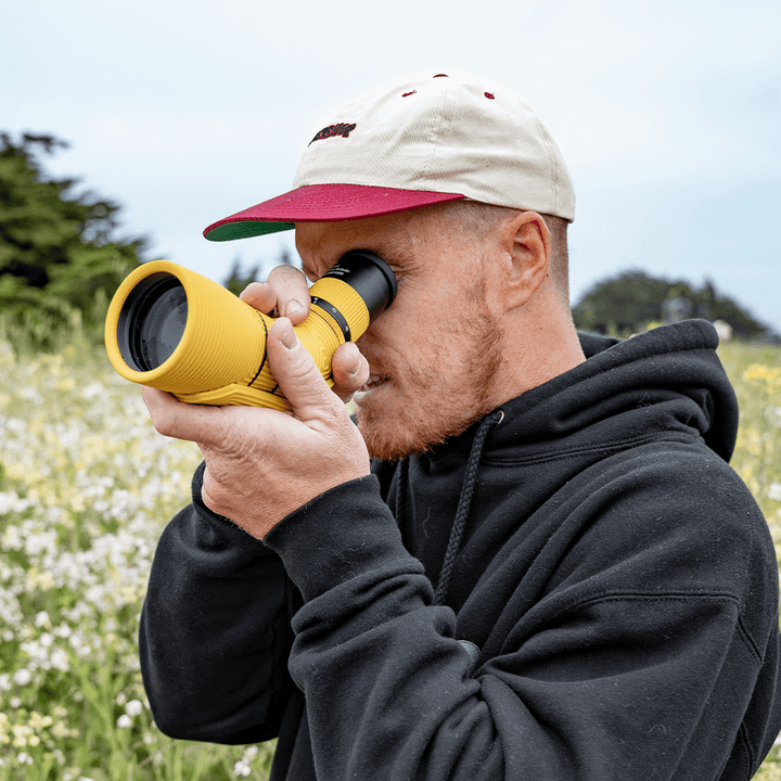 Man using a yellow spotting scope in a natural setting