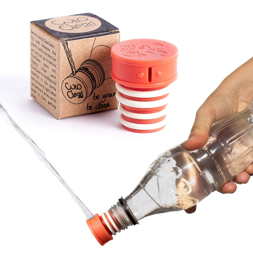 Orange portable bidet screwed onto a plastic bottle and squirting water, packaging in background
