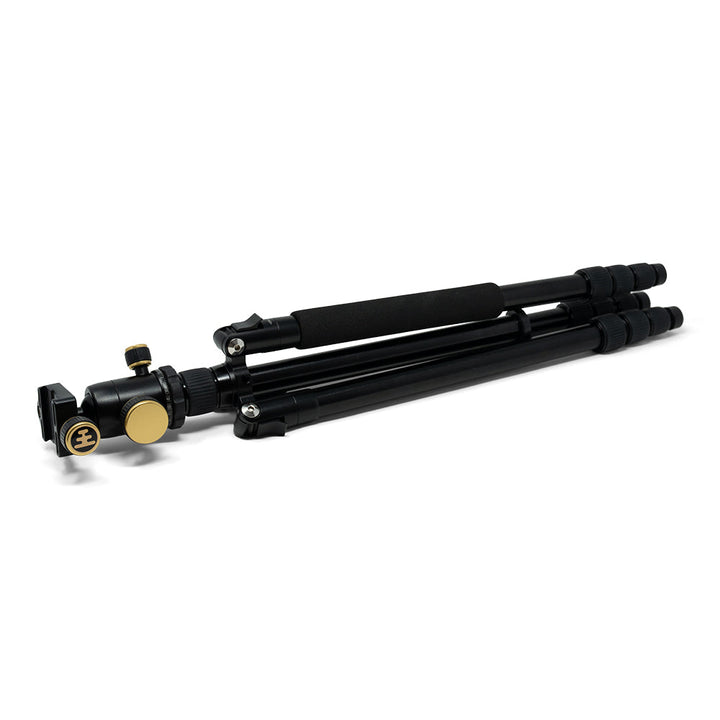 Black tripod with gold fittings, packed up, on a white background