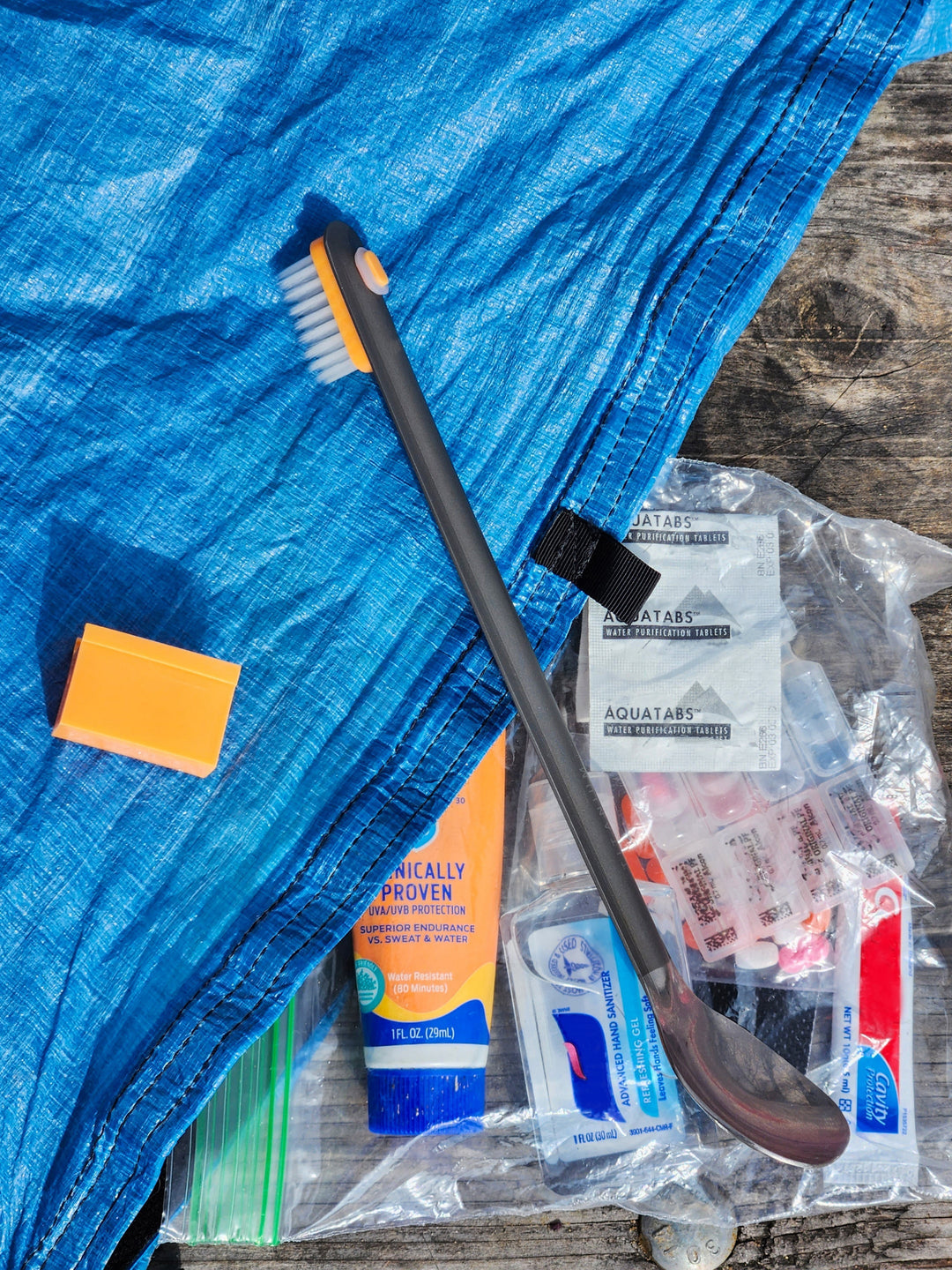 Collection of hiking toiletries with a toothbrush head clipped to a metal spoon