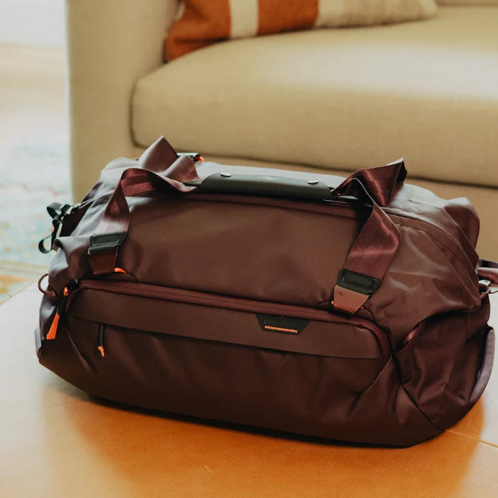 Brown duffel bag with handles on a wooden surface with a blurred background