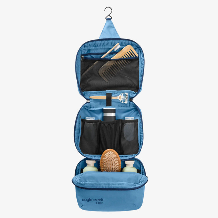 Blue hanging toiletry bag with grooming items on a white background