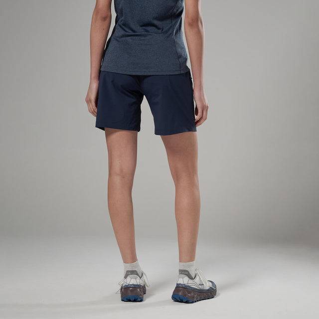Person wearing navy shorts and grey shoes on a neutral background