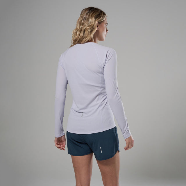 Woman wearing a light purple long-sleeve athletic shirt and dark blue shorts on a grey background
