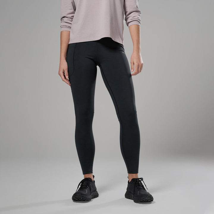 Person wearing black leggings and a light-colored top on a grey background